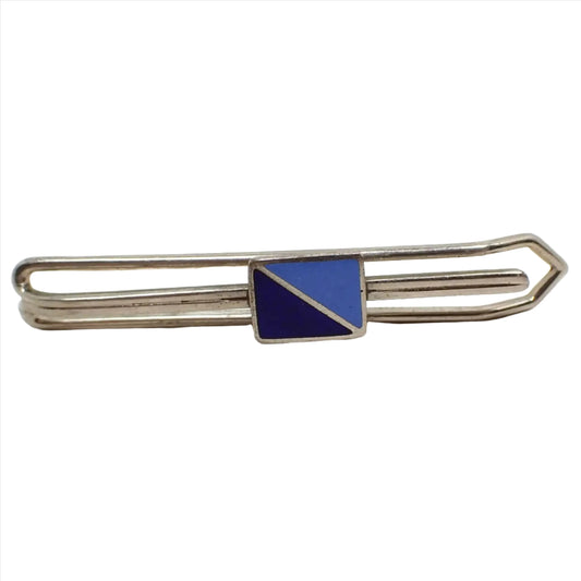 Front view of the Mid Century vintage slide on tie bar. It has an open wire style design in silver tone color metal. On the front in the middle is a rectangle that is split diagonally into two triangles. One triangle has dark blue enamel and the other has a lighter blue enamel.