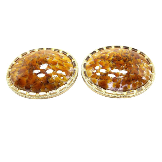 Front view of the very large Mid Century vintage fancy glass cufflinks. They are oval in shape with a rectangle dash edge. The metal is gold tone in color. The domed glass cabs have an abstract pattern of orange, yellow, and white.