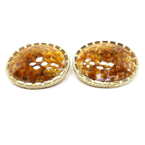 Front view of the very large Mid Century vintage fancy glass cufflinks. They are oval in shape with a rectangle dash edge. The metal is gold tone in color. The domed glass cabs have an abstract pattern of orange, yellow, and white.