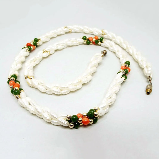 Retro vintage glass and faux pearl beaded necklace from the 1980's. The necklace has strands of rice shaped glass imitation pearls. There are four clusters of green and salmon orange color glass beads. The end has a screw barrel clasp. Clasp and metal beads are gold tone in color.