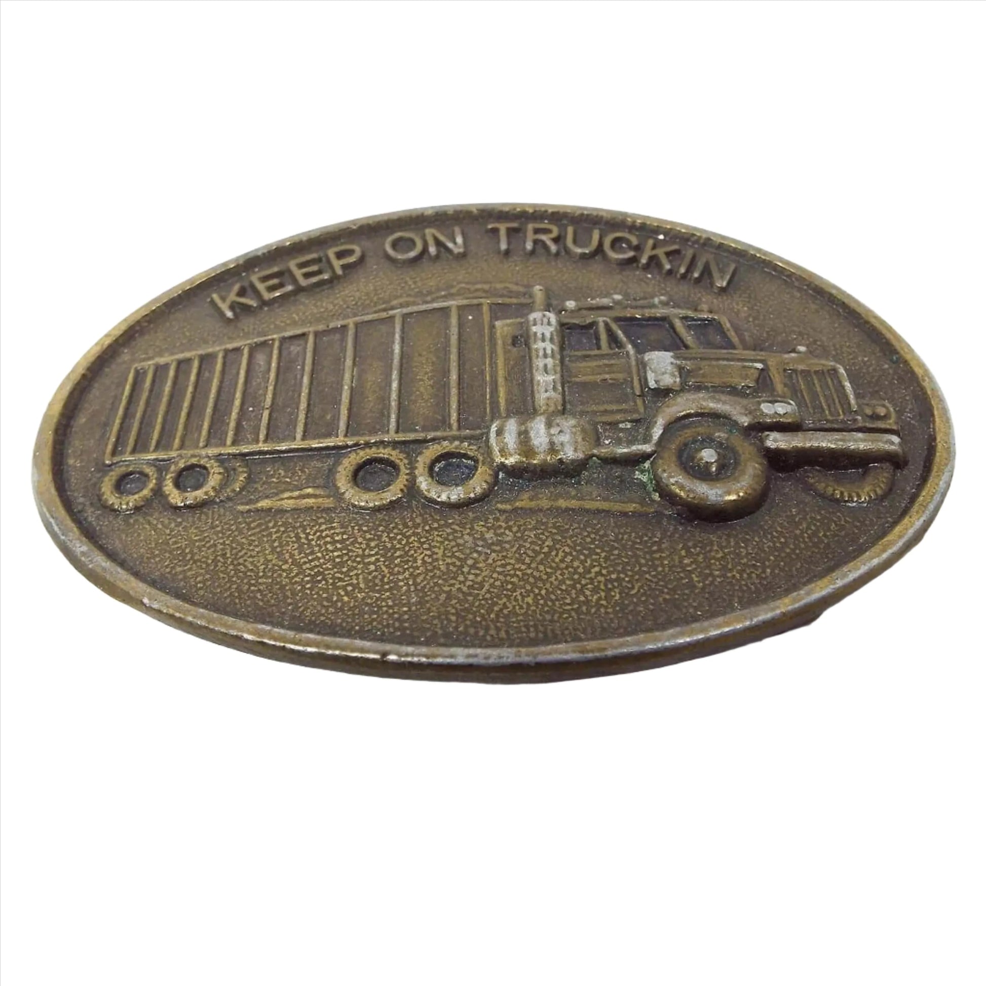 Front view of the retro vintage trucker's belt buckle. It is oval and antiqued brass in color. It says Keep on Truckin on the top and has a semi with trailer on it. There are some scuffs on the front of the truck area.