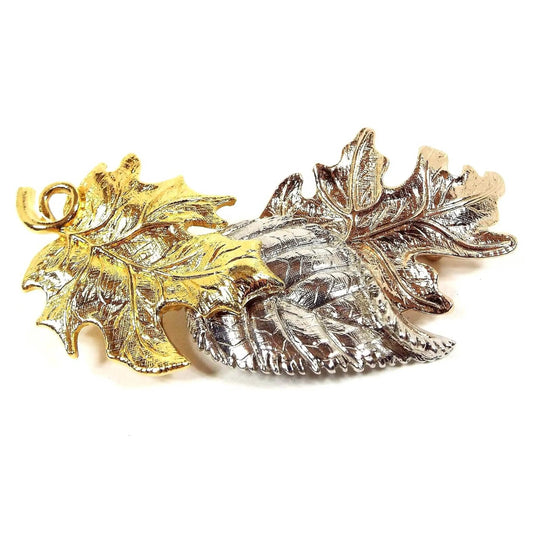 Front view of the retro vintage Avon leaves brooch pin. There are three different styles of leaves together. One is gold tone, one is silver tone, and the third is copper tone in color.