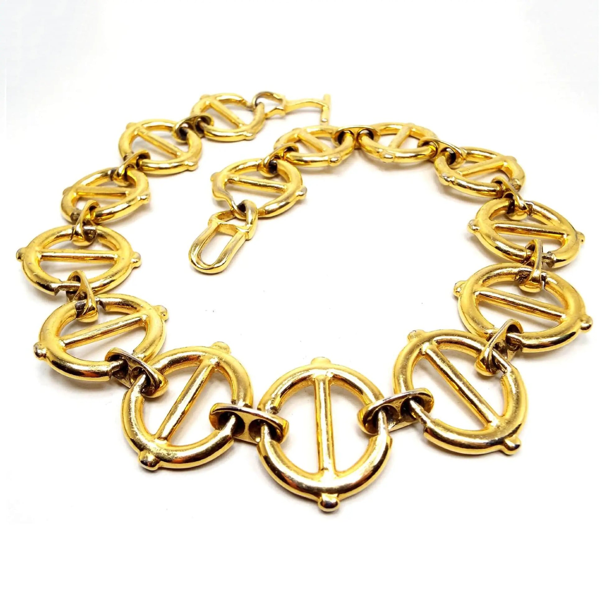 Top view of the retro vintage large wide link necklace. The metal is gold tone in color. The links are large and round with a bar through the middle and they are held together by smaller sized oval links with holes. There is a large toggle clasp at the end.