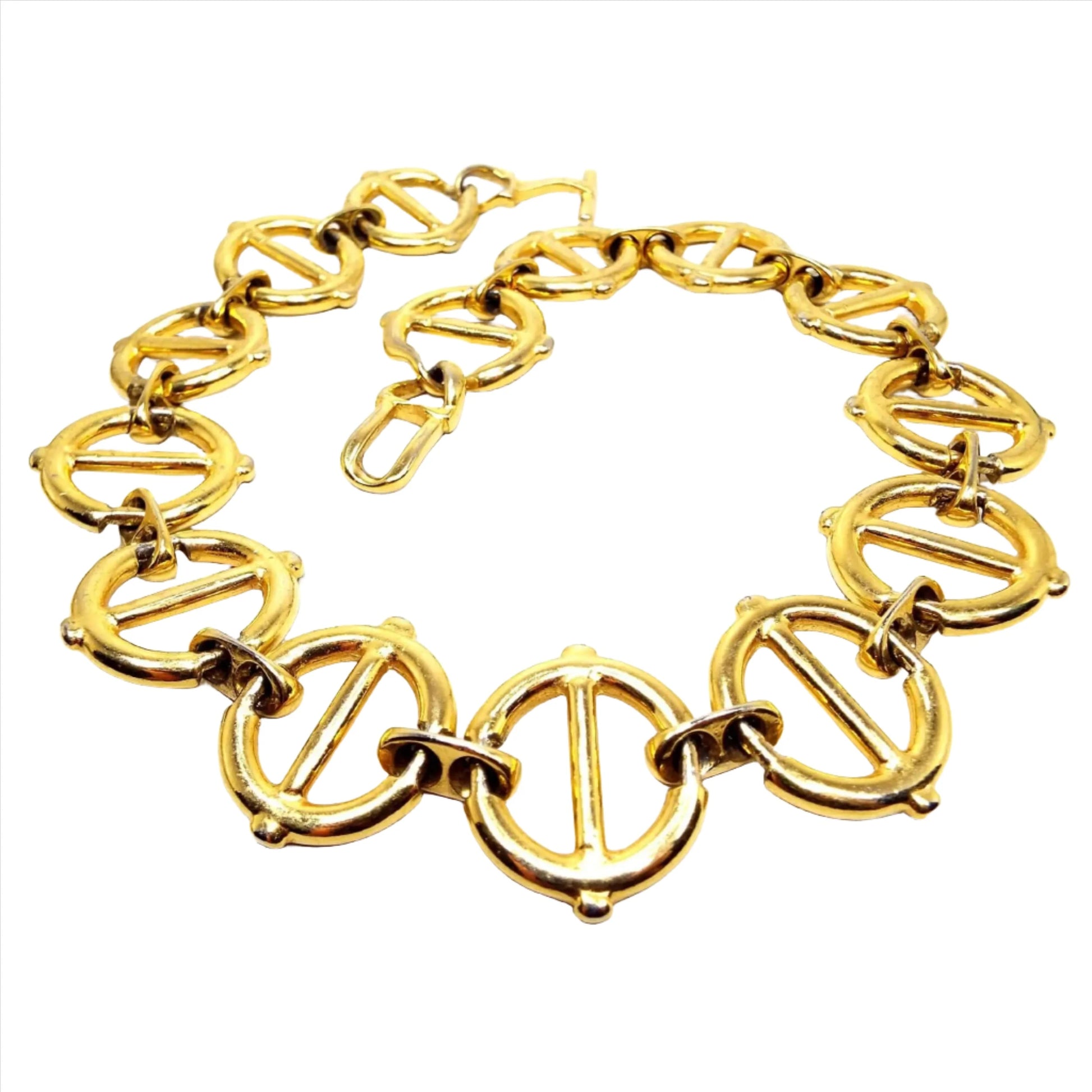 Top view of the retro vintage large wide link necklace. The metal is gold tone in color. The links are large and round with a bar through the middle and they are held together by smaller sized oval links with holes. There is a large toggle clasp at the end.