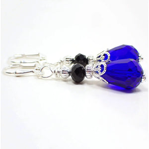 Side view of the handmade glass crystal teardrop earrings. The metal is silver plated in color. There is a faceted black rondelle bead at the top and a bright cobalt blue color faceted teardrop bead at the bottom.
