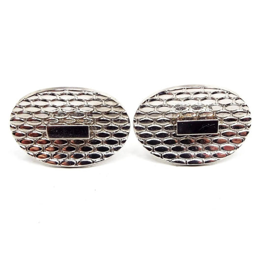 Front view of the retro vintage geometric cufflinks. They are silver tone in color with an oval shape. There is a raised oval pattern all across the front and a single rectangle in the very middle.