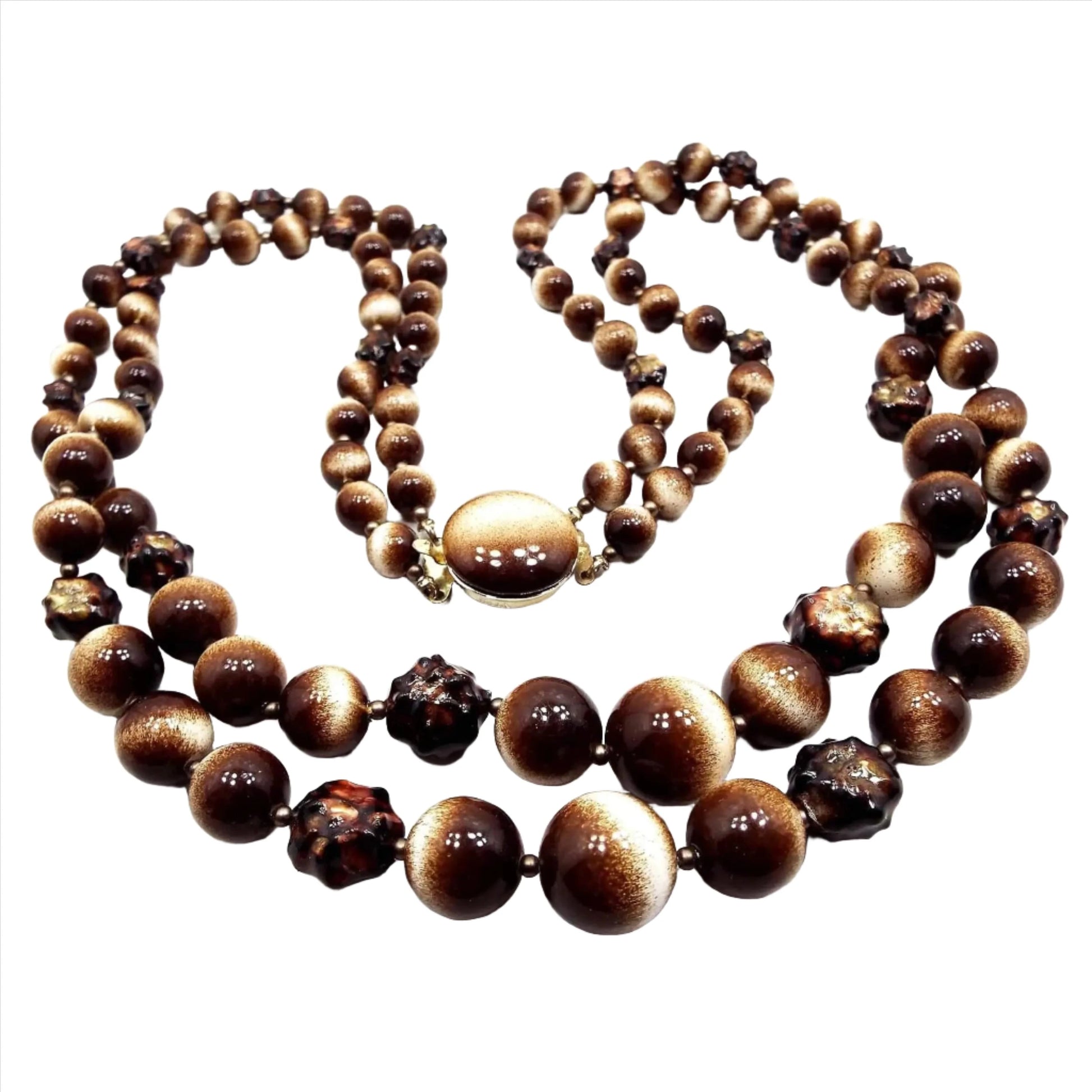 Front view of the Mid Century vintage multi strand beaded necklace from Japan. There are two strands of mostly round beads in dark brown and white. There are some dark chunky brown beads here and there throughout the necklace. At the end is a box clasp with a flat plastic top with the same dark brown and white shading.