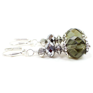 Side view of the handmade glass beaded drop earrings. The metal is silver plated in color. There are faceted metallic silvery gray glass beads at the top. The bottom beads are faceted glass as well and are a smoky green color that takes on a brownish gray hue depending on the lighting.
