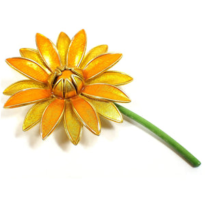 Front view of the Mid Century vintage German floral brooch pin. The brooch is shaped like a flower with a green stem and orange and yellow petals. The petals and stem are lightly enameled.