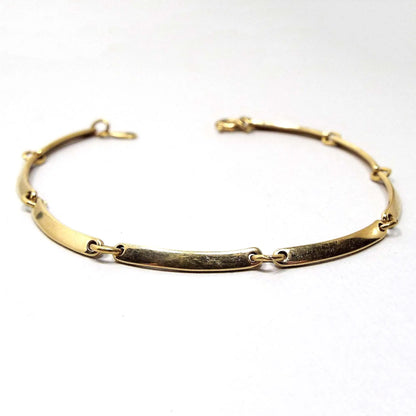 Angled view of the retro vintage Avon link bracelet. The metal is gold tone in color. The links are flattened style long slightly curved oval links held together with metal jump rings. There is a round spring ring clasp at the end.