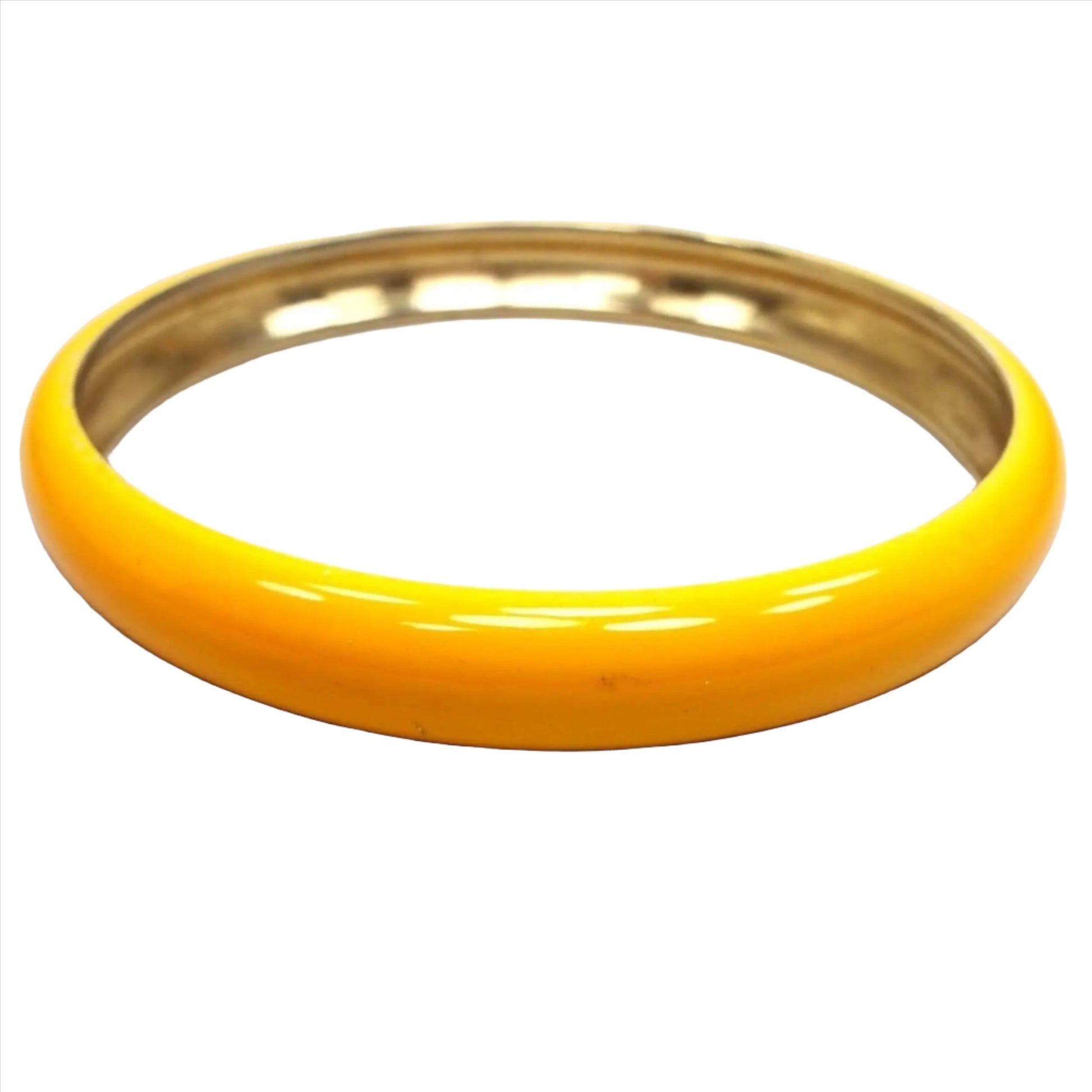 Angled top and side view of the retro vintage bangle bracelet. The outer edge is curved and enameled with a dark yellow color that has some shades of orange as you get to the middle. The inside of the bangle is gold tone metal color.
