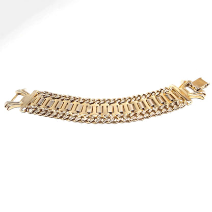 Angled view of the Mid Century vintage wide link chain bracelet. It is gold tone in color and has curved rectangle links the in the middle and faceted curb link chain on either side. There is a large snap lock clasp on the end.