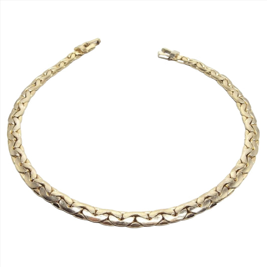 Top view of teh retro vintage chain necklace. The metal is gold tone in color. It has a flattery style C link chain design with a snap lock clasp on the end.