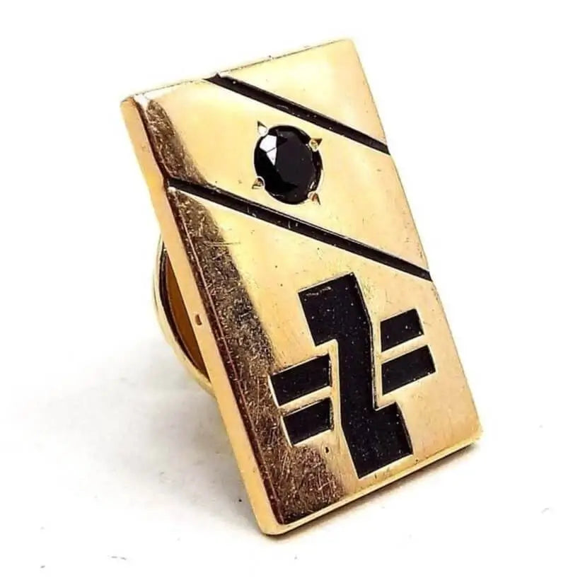 Tie Tack is a gold color rectangle shape. It has two black diagonal lines at the top right with a black faceted onyx gemstone in between them. On the bottom center is a black initial letter Z with two black lines coming out from each side. 