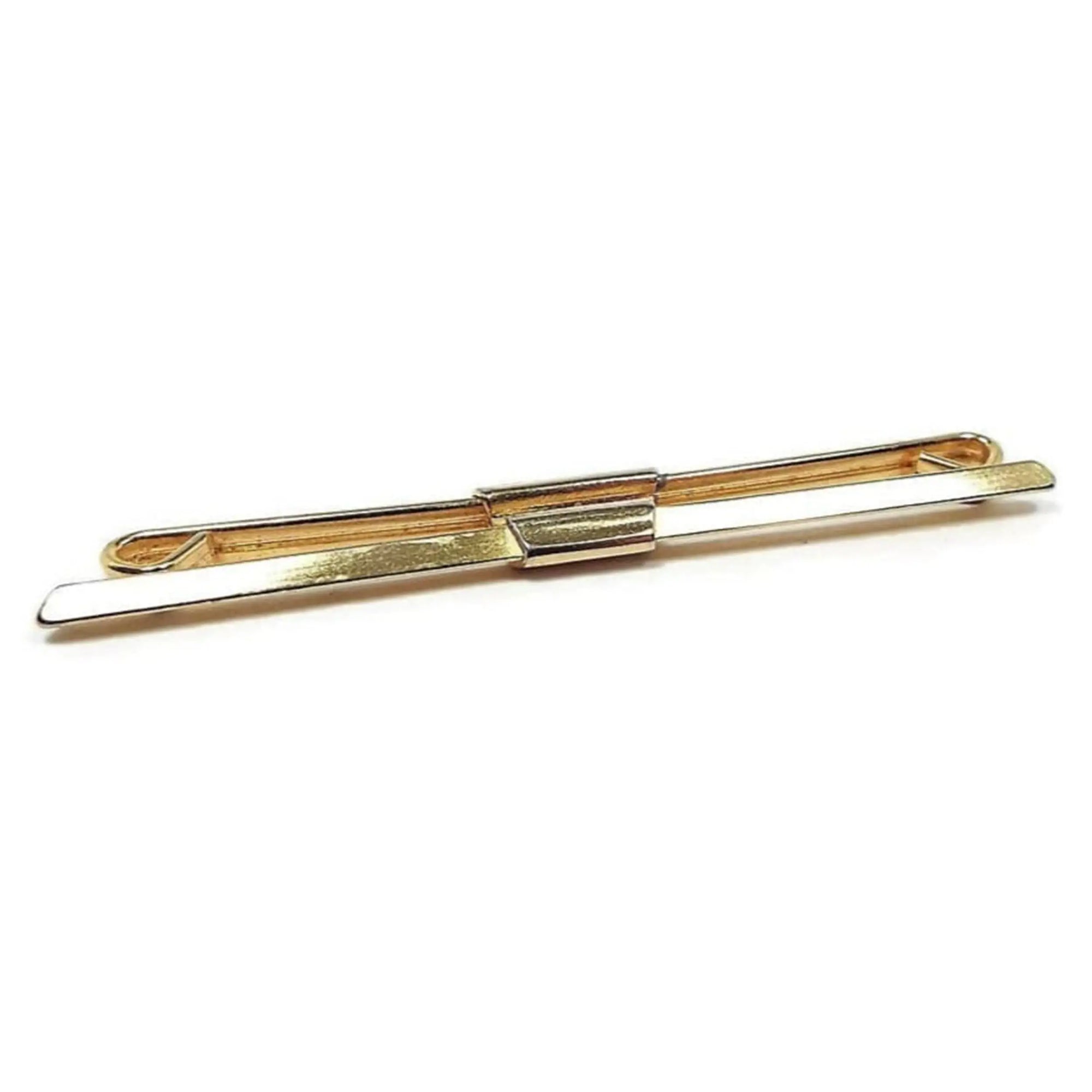 Angled front and side view of the Mid Century vintage collar clip bar. The metal is gold tone in color. The front of the bar is straight and has a tapered angled front edge. The back bar is straight and curls inwards at the ends. There is a rectangular piece in the middle that secures the bars together.