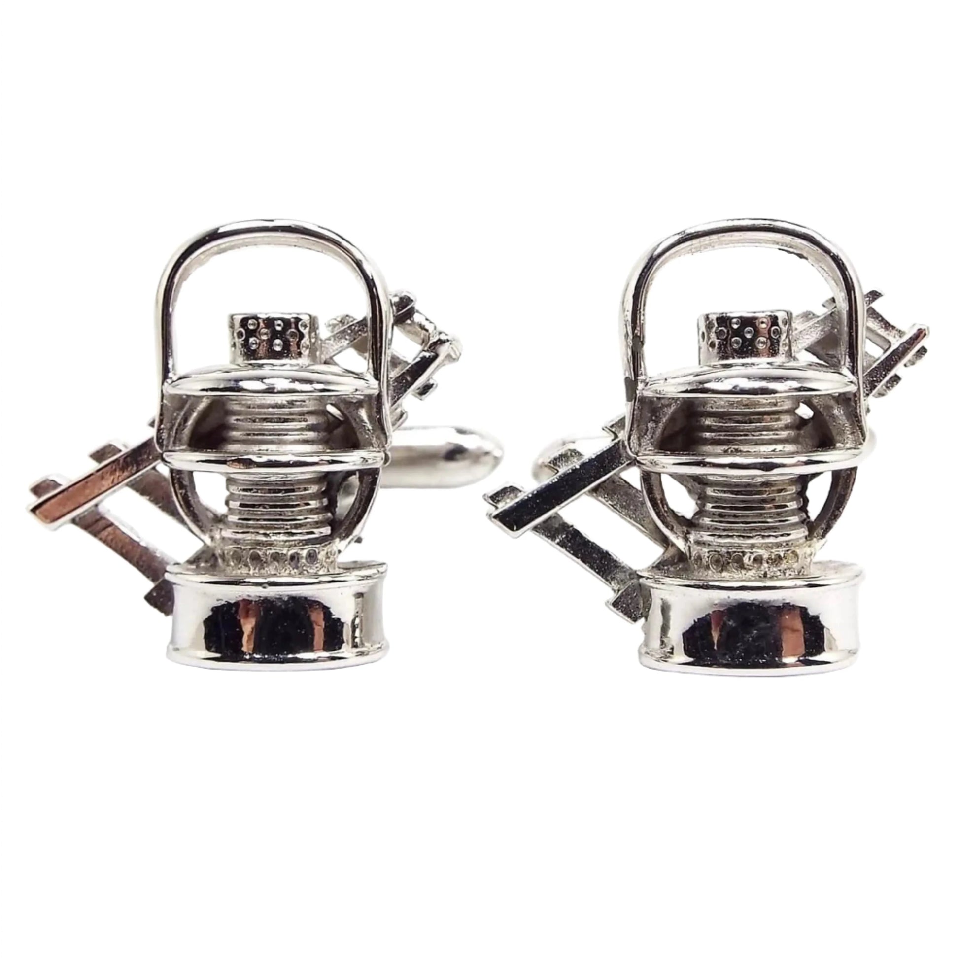 Front view of the Mid Century vintage Swank mining cufflinks. The fronts have a 3D style design of mining lamps with a cart railway behind it. They are silver tone in color.