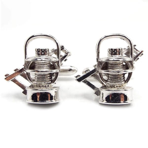 Front view of the Mid Century vintage Swank mining cufflinks. The fronts have a 3D style design of mining lamps with a cart railway behind it. They are silver tone in color.