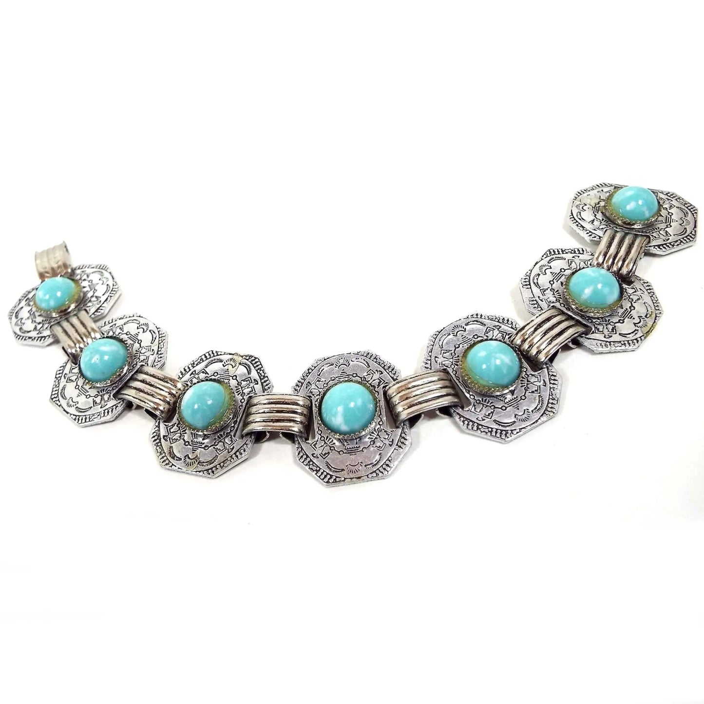 Top view of the Mid Century vintage link bracelet. Each link has a blue and white marbled plastic cab. The metal is silver tone in color and the links have a stamped Southwestern tribal style design.