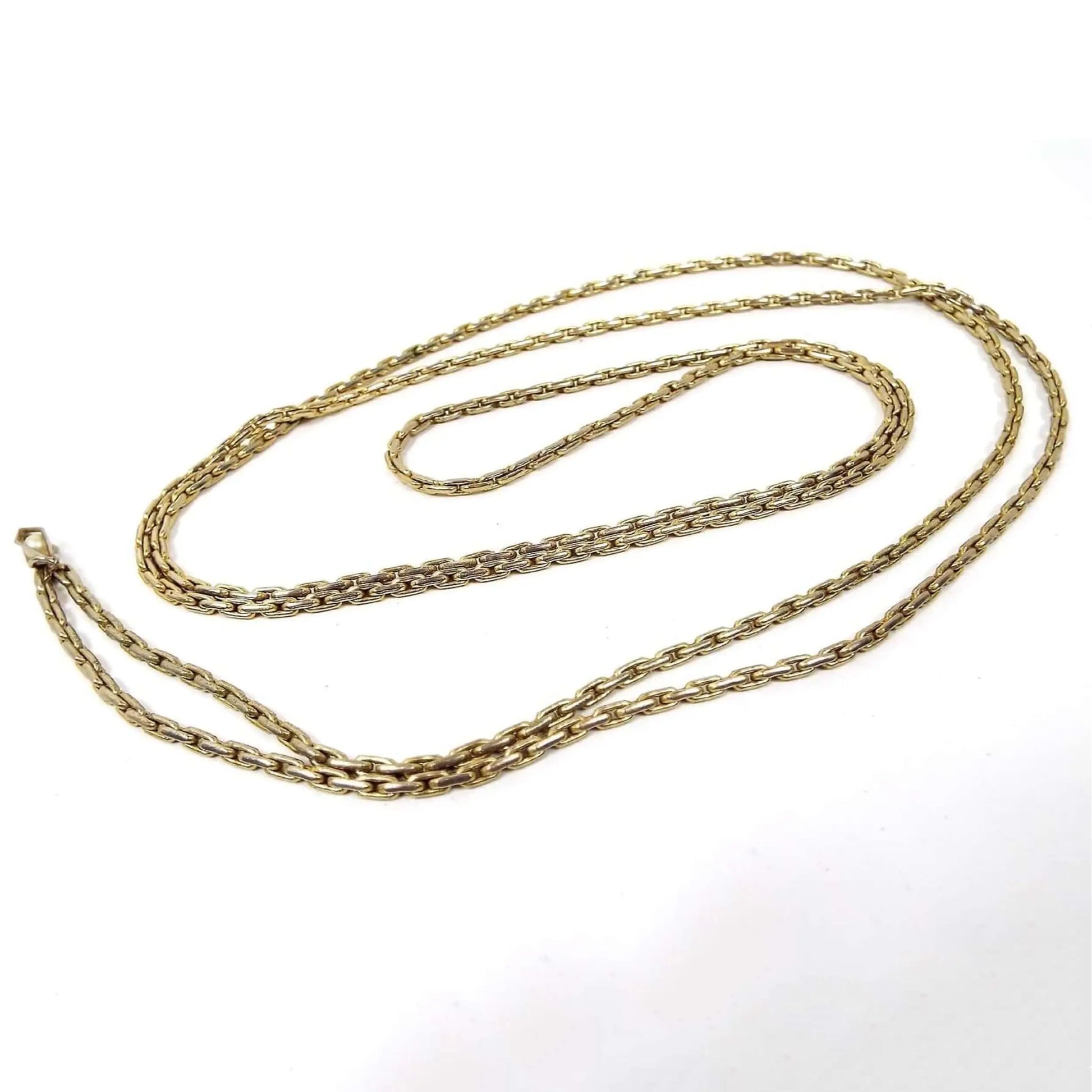 Top view of the retro vintage square link chain necklace. The metal is gold tone in color and a fancy rounded edge square link design. At the end there is a small faceted bottom teardrop charm with a faux pearl in it. There is no clasp as it's long and goes over your head.