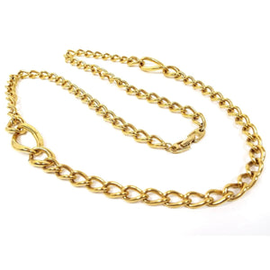 Top view of the retro vintage Napier chain necklace. It is gold tone in color with a curved oval curb chain design. There are two areas on either side that have sets of three links that are larger in size with the largest in the middle. There is a snap lock clasp on the end.