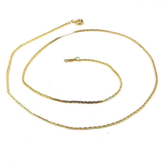 Chain is gold in color with small square links. Each link alternates between the square being up and down or sideways. Clasp is a round spring ring clasp.