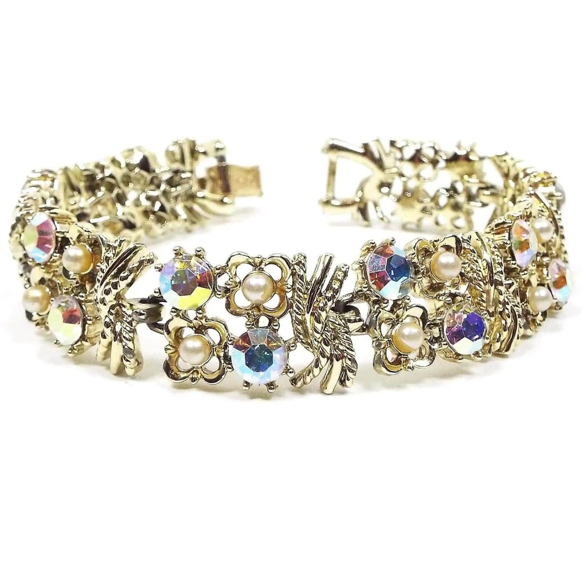 Front view of the top of the Mid Century vintage Coro rhinestone and faux pearl bracelet. It is gold tone in color and has a filigree floral design. Some of the flowers have AB rhinestones in the middle and others have small imitation pearls in them. There is a snap lock clasp at the end.