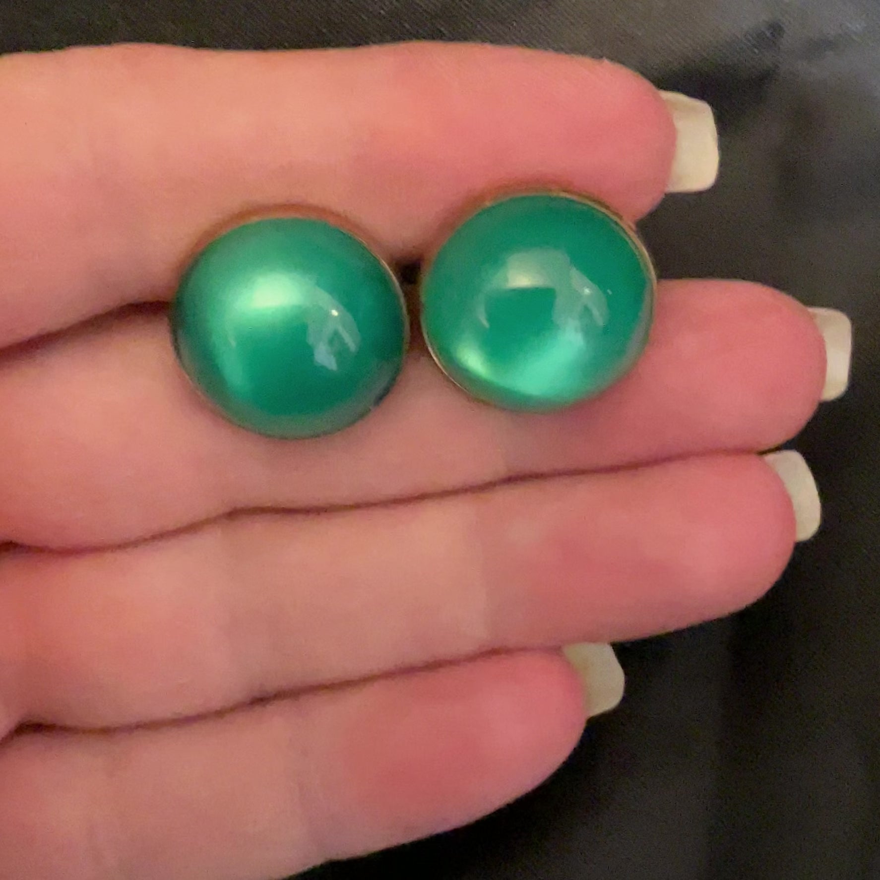 Video of the Mid Century vintage green moonglow lucite cufflinks showing how they have an inner glow like appearance when the light hits them.