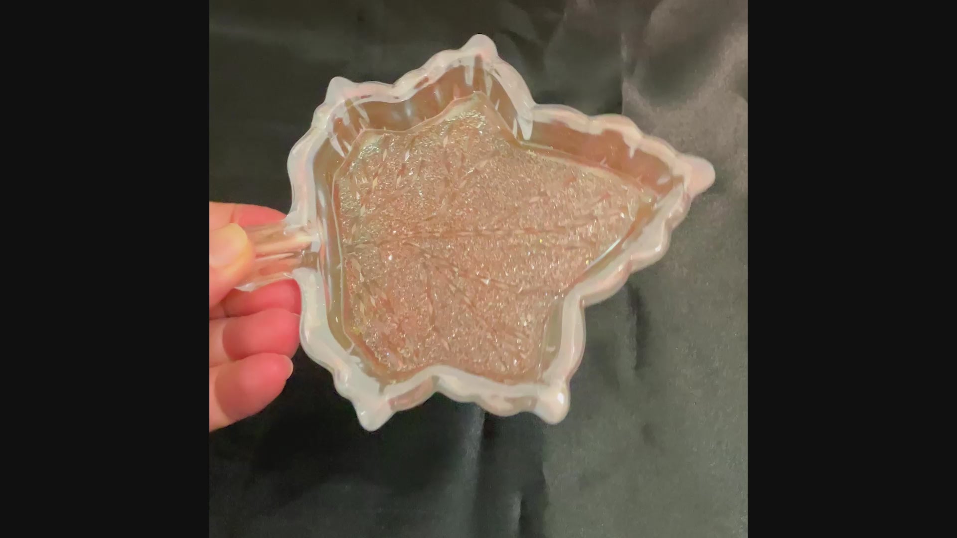 Video of the handmade opalescent and colorshift resin leaf decorative trinket dish showing how the bottom faceted crystal like area sparkles in the light.