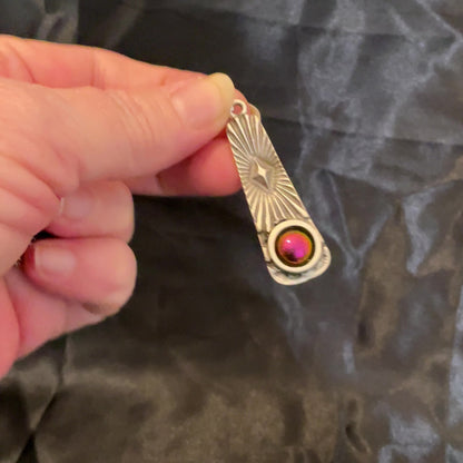 Video of the resin cab on the atomic star necklace showing how it goes from pink to orange, green, and yellow depending on how the light hits it.