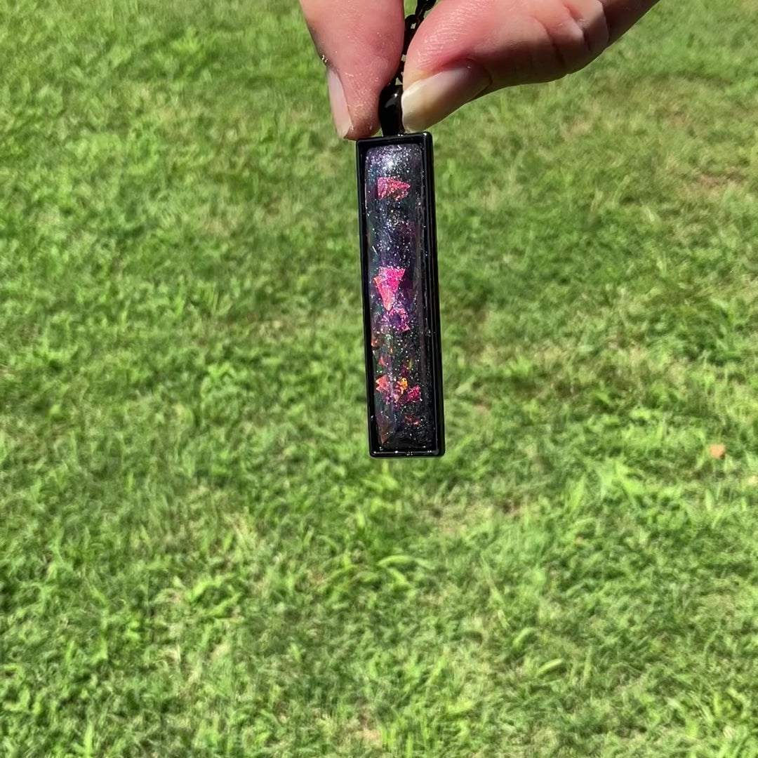 Dark Purple Handmade Resin Black Bar Pendant Necklace with Chunky Iridescent Glitter video showing how the glitter flashes different colors in the light as it moves around.