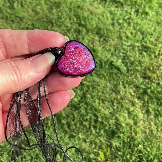 Handmade Goth Bright Pink and Purple Resin Black Heart Pendant Necklace with Iridescent Glitter video showing how the glitter sparkles in the light.