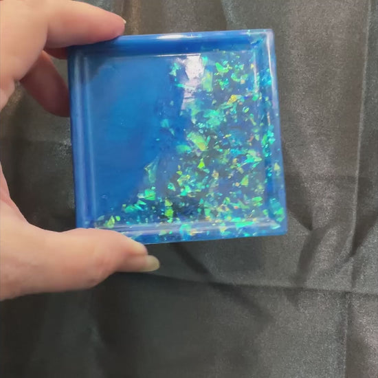 Video of the small handmade square trinket dish in ocean blue showing how the iridescent glitter flakes sparkle and flash in the light.