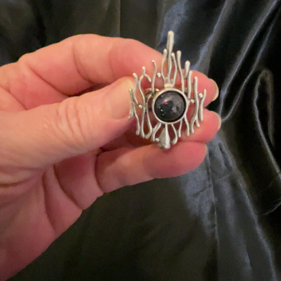 Video showing how the holographic black glitter on the handmade brutalist style adjustable ring sparkles in the light as it moves around.