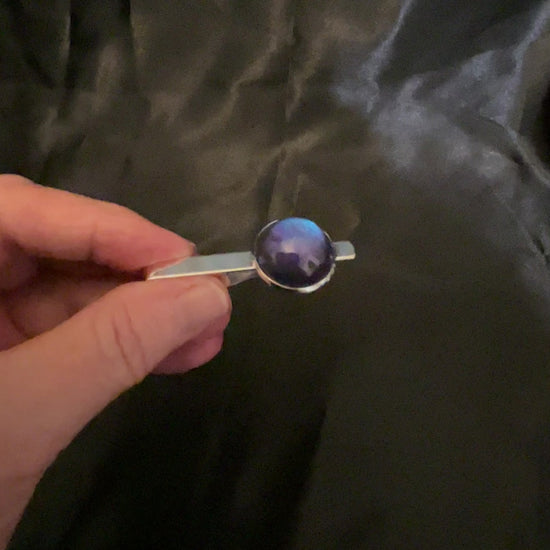 Video showing the tie clip from the handmade men's color shift jewelry set showing how the resin cab shifts from purple to blue depending on how the light hits it.