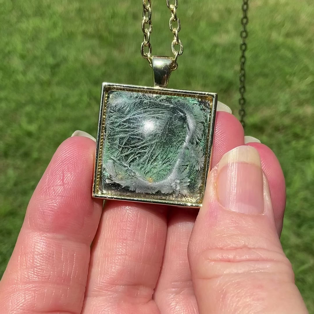 Handmade Iridescent Green with Abstract Frost Resin Pendant Necklace video showing how the square pendant has iridescent shades of green and golden yellow as it moves around in the light.