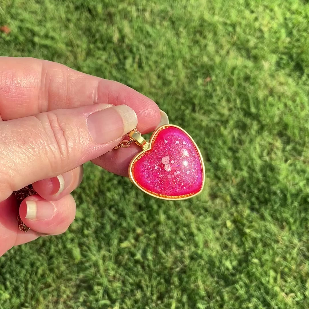 Handmade Gold Plated Bright Pink Resin Heart Pendant Necklace with Iridescent Glitter video showing how the glitter sparkles in the light.