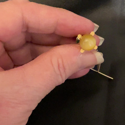 Video showing how the Mid Century vintage golden yellow glass faux cat's eye tie tack has flash as it moves around in the light.