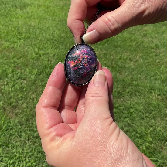Large Oval Handmade Purple Resin Pendant Necklace with Iridescent Glitter video showing how the glitter flashes different colors as it moves around in the light.
