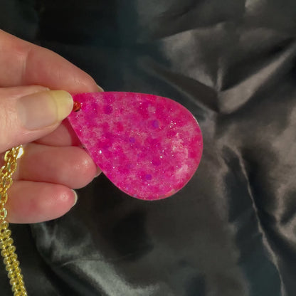 Video of the handmade resin necklace in the jewelry set showing how the pink glitter in the teardrop pendant sparkles in the light.