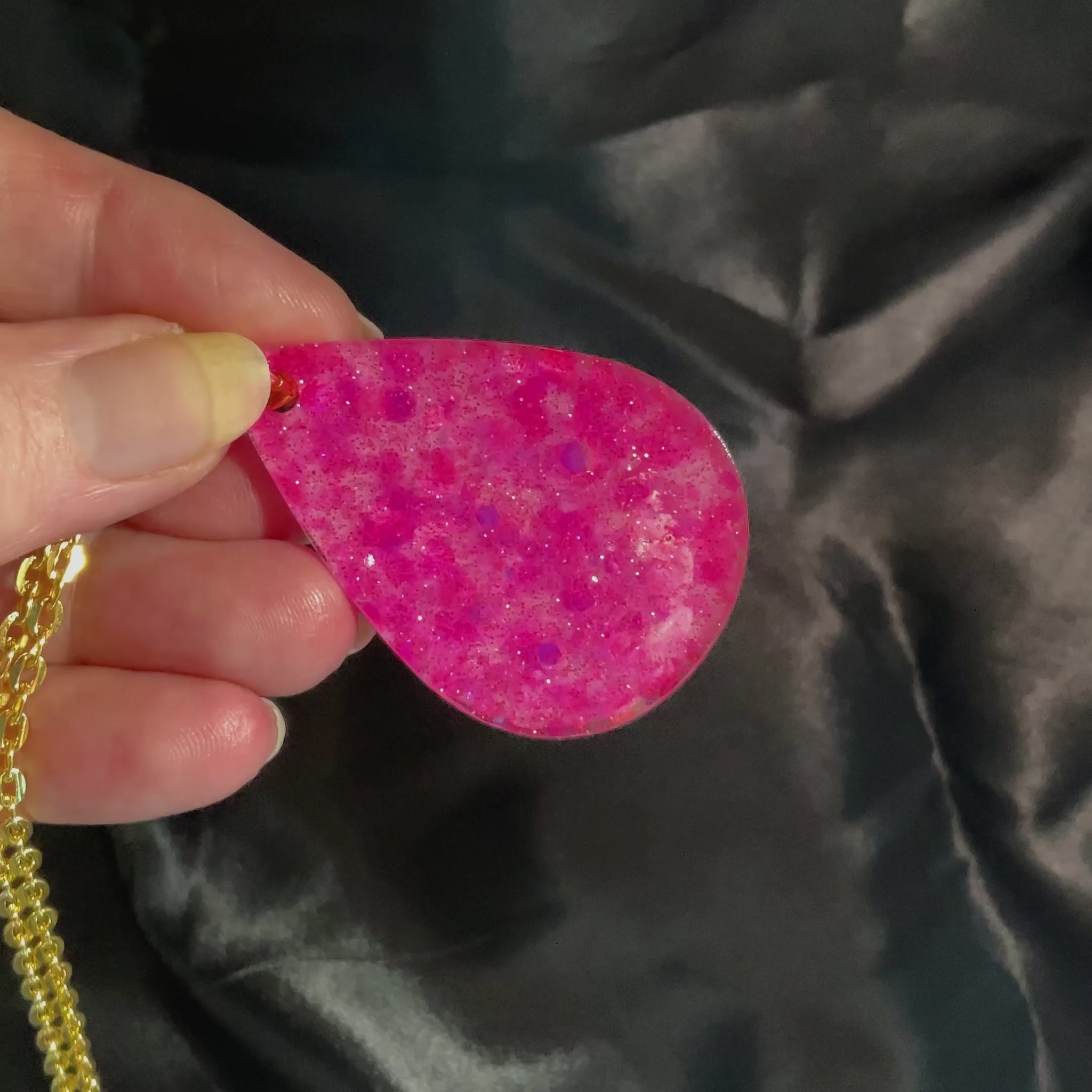 Video of the handmade resin necklace in the jewelry set showing how the pink glitter in the teardrop pendant sparkles in the light.