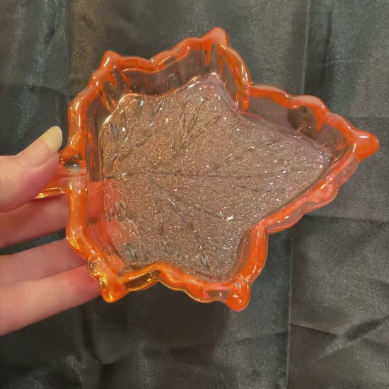 Video of the handmade orange and pink resin Fall leaf decorative trinket dish showing how the crystal style design on the inside sparkles in the light.