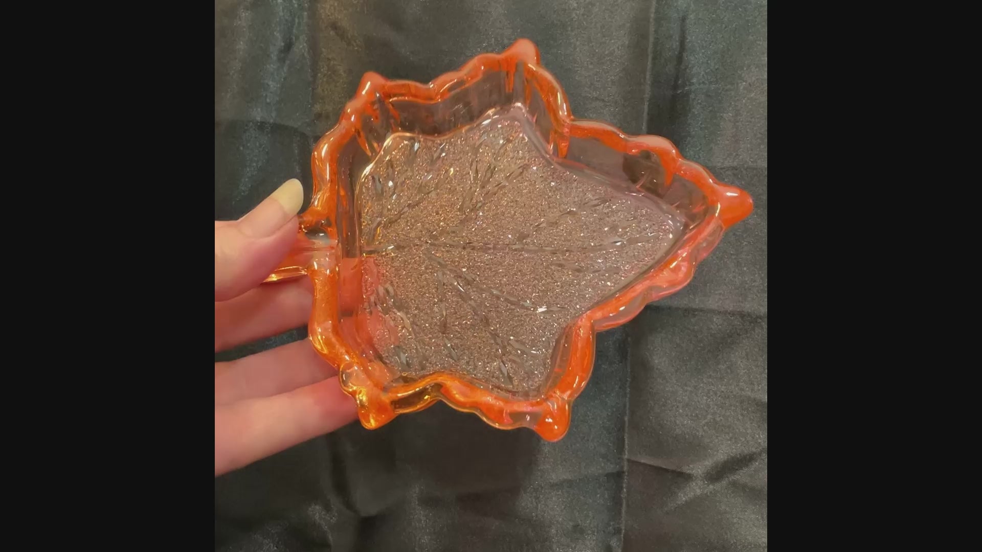 Video of the handmade orange and pink resin Fall leaf decorative trinket dish showing how the crystal style design on the inside sparkles in the light.