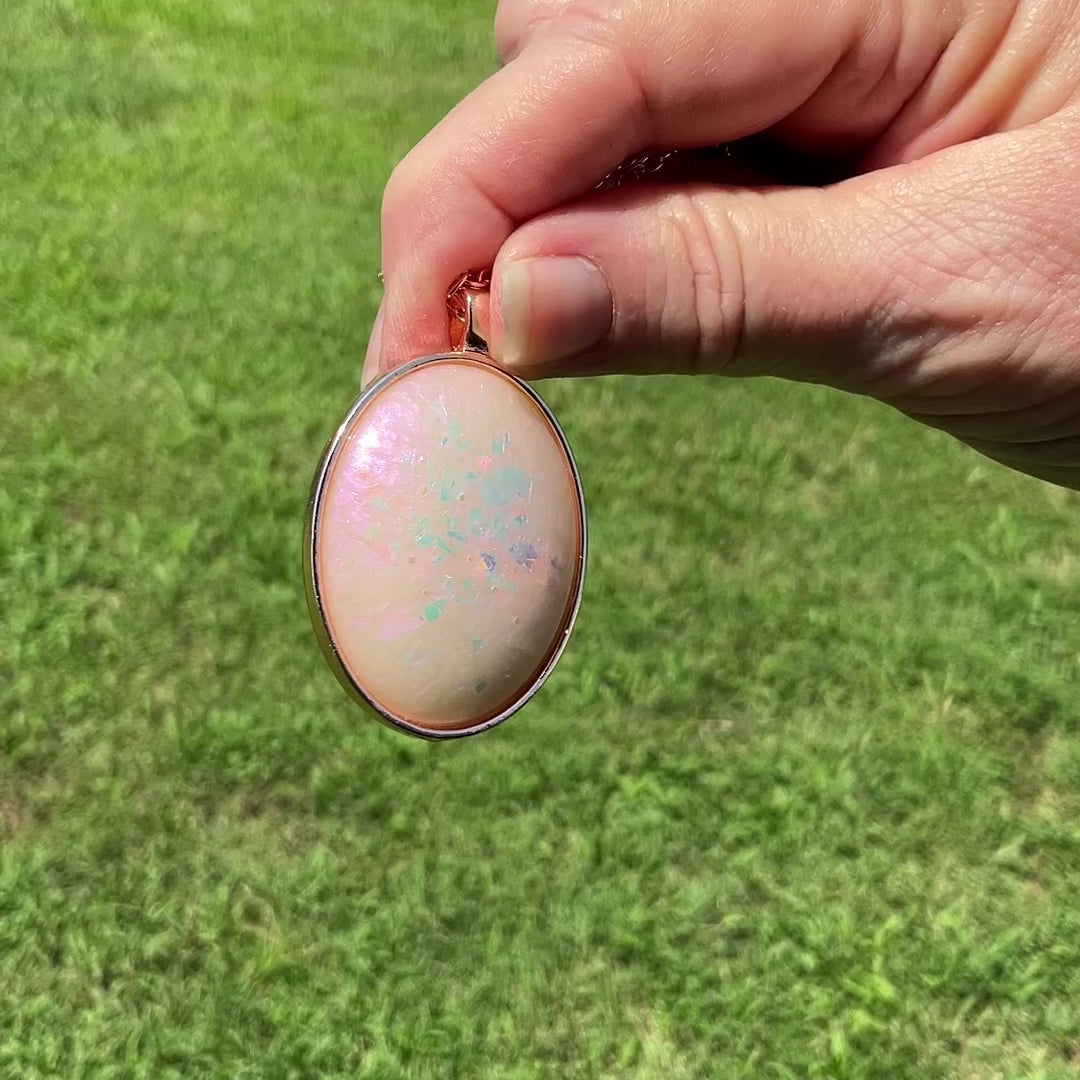Handmade Off White and Pink Color Shift Resin Oval Glitter Pendant Necklace video showing the pink sheen and glitter color flash and sparkle in the light.