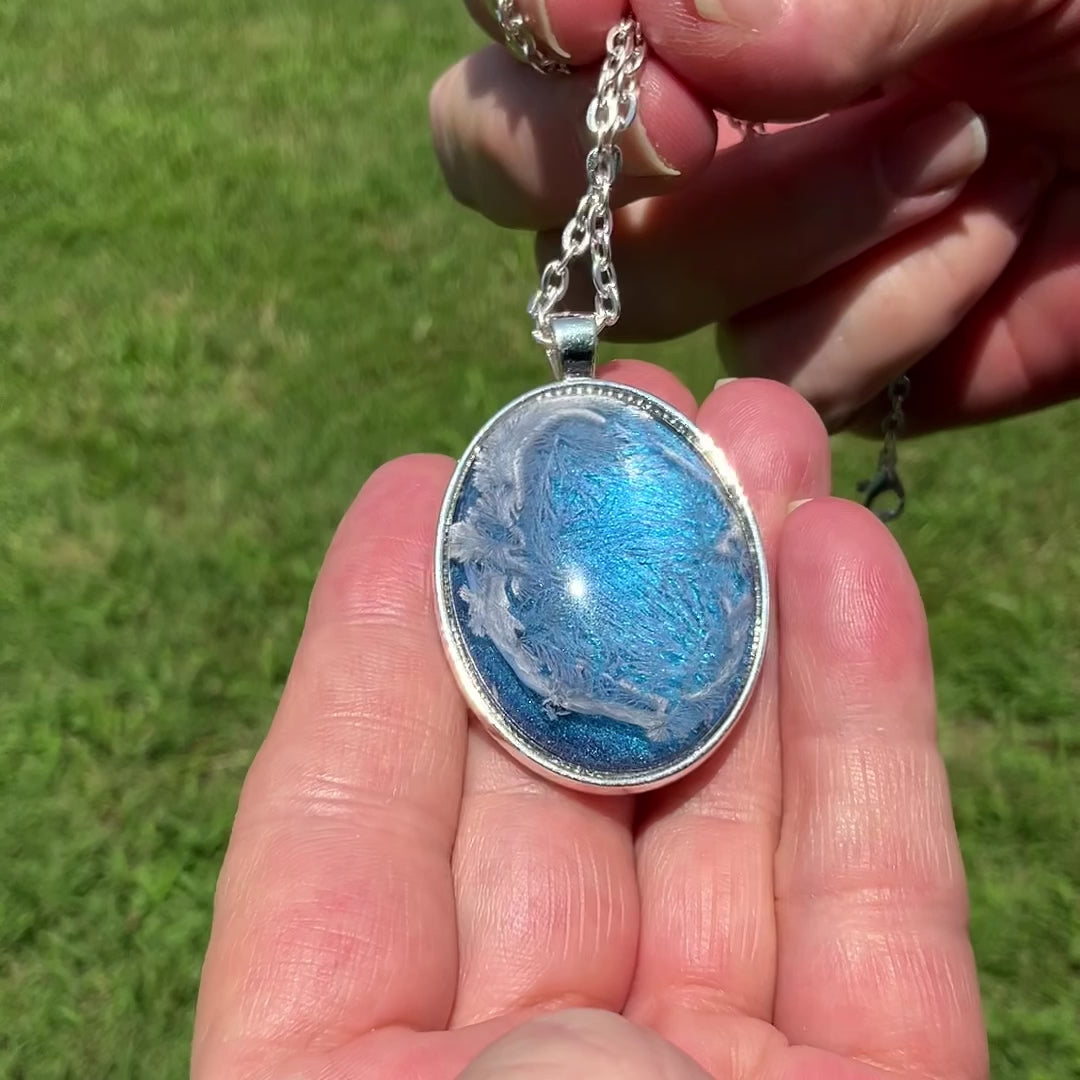 Large Oval Handmade Abstract Blue Frost Resin Pendant Necklace video showing how the iridescent background shimmers and changes shade in the light.