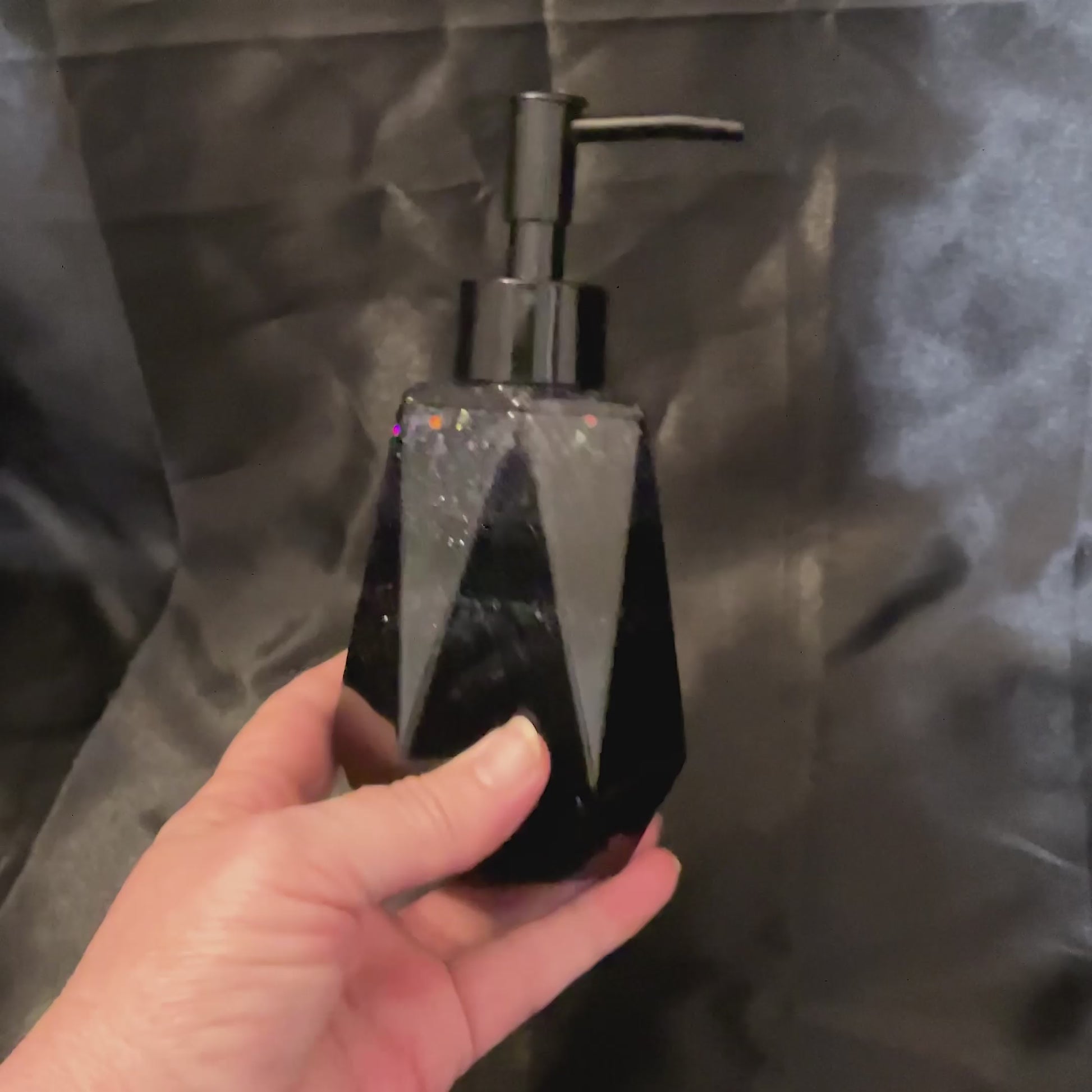 Video of the black glitter soap dispenser showing how there are bands of black resin and glitter resin and how the glitter sparkles in the light.