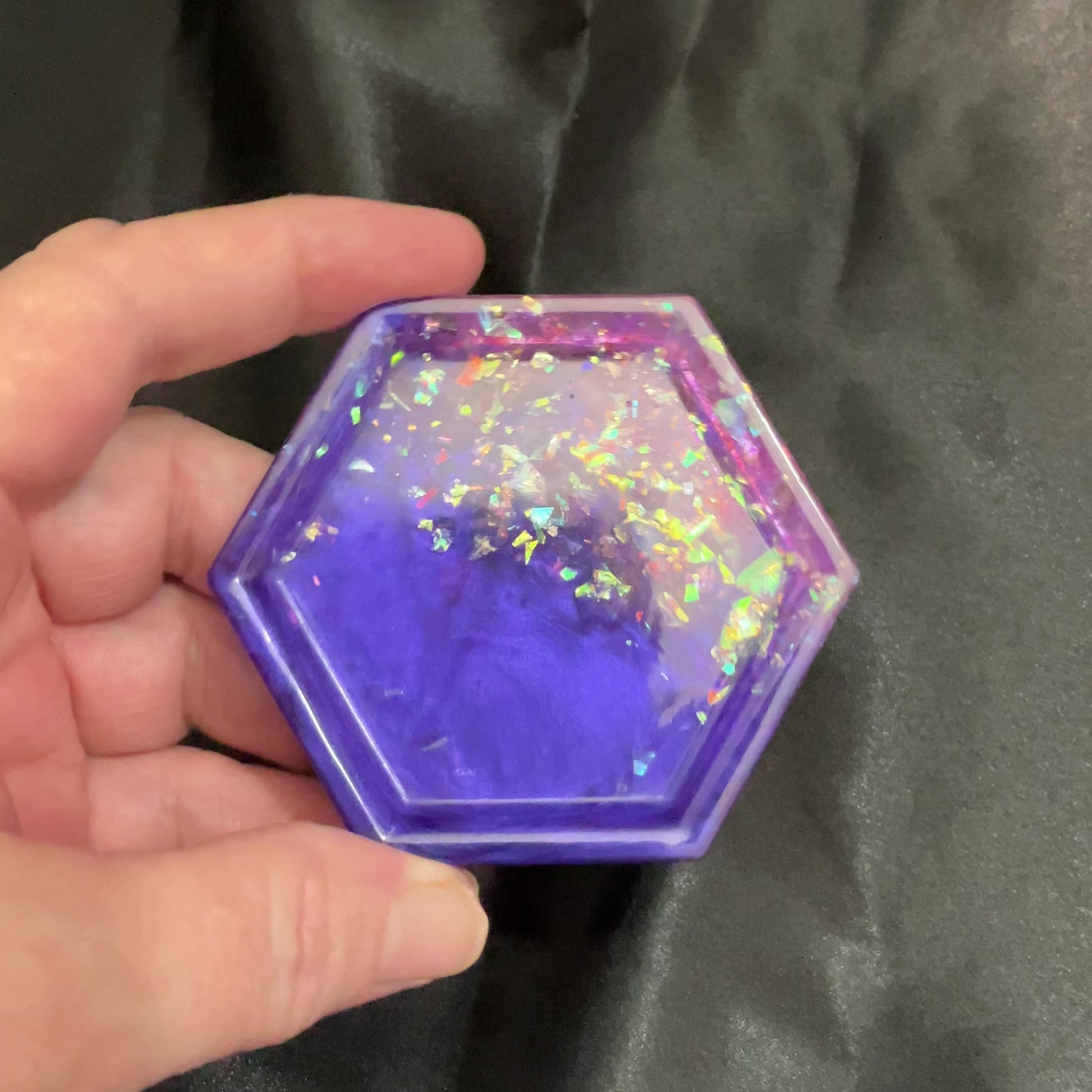 Video of the handmade geometric octagon purple and pink resin trinket dish with iridescent flakes showing how it sparkles and has flashes of color in the light.