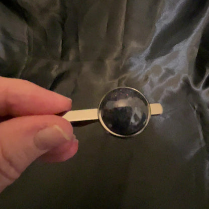 Video of the holographic black tie clip showing how the iridescent glitter sparkles in different colors as the light hits it.