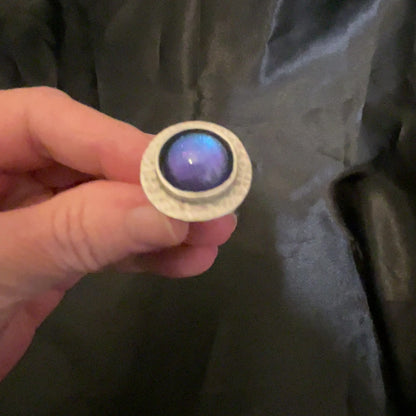 Video of the handmade domed round hammered adjustable ring showing how the color shift resin cab goes from blue to purple as the light hits it.