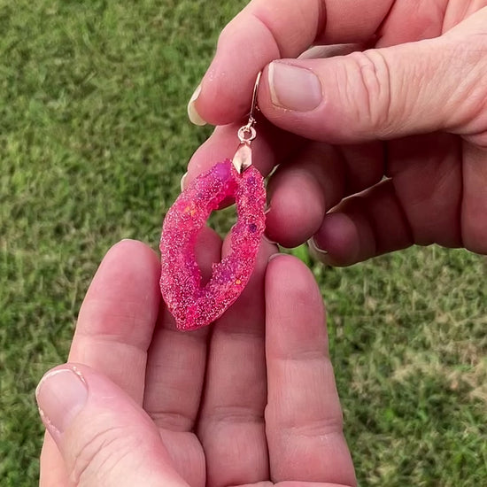 Video of the handmade bright pink geode style resin earrings showing how the glitter sparkles in the light.