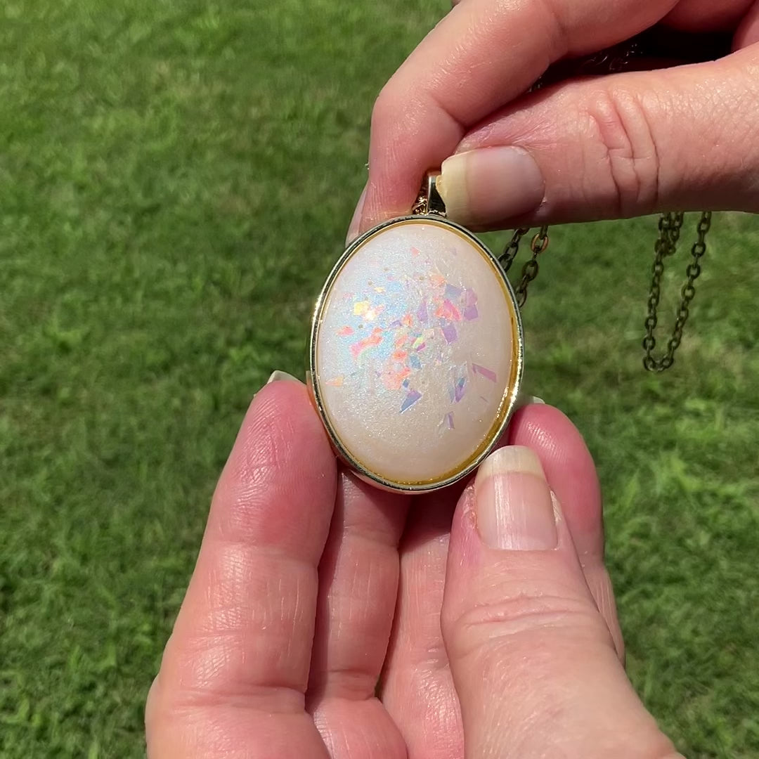Handmade Blue Opal Color Shift Resin with AB Pink Glitter Oval Pendant Necklace video showing the blue sheen and color flash sparkle of the glitter. 